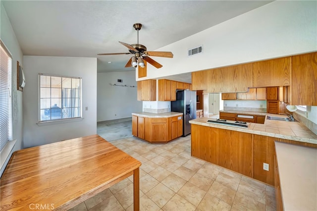 kitchen with lofted ceiling, ceiling fan, stainless steel appliances, sink, and kitchen peninsula