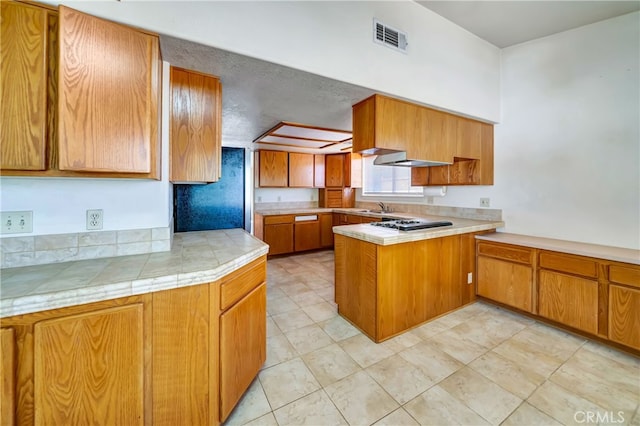 kitchen featuring light tile patterned flooring, gas cooktop, sink, kitchen peninsula, and a textured ceiling