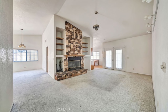 unfurnished living room with a stone fireplace, light colored carpet, and a healthy amount of sunlight