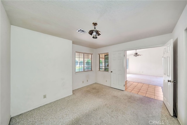 carpeted spare room featuring ceiling fan and a textured ceiling