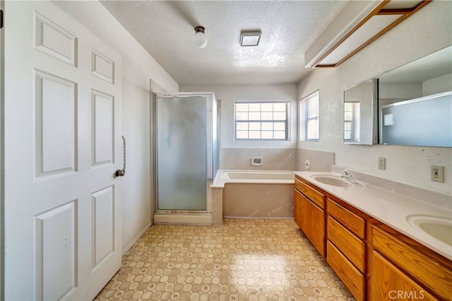 bathroom featuring shower with separate bathtub, vanity, and a textured ceiling