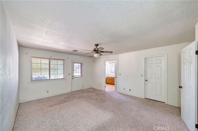 carpeted empty room with ceiling fan and a textured ceiling