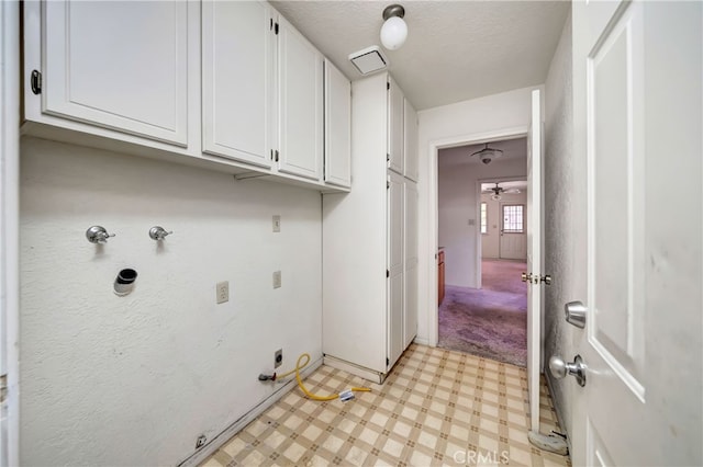 laundry area with ceiling fan, hookup for an electric dryer, a textured ceiling, gas dryer hookup, and cabinets