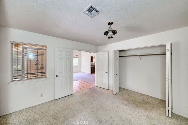 unfurnished bedroom with a textured ceiling, a closet, and carpet flooring