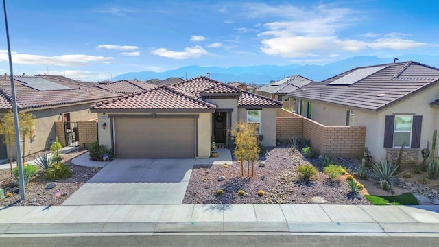 view of front of home featuring a garage, a mountain view, and solar panels