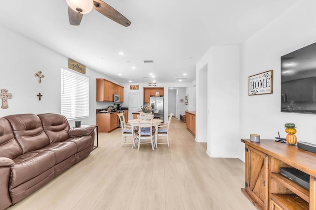 living room featuring ceiling fan and light hardwood / wood-style flooring