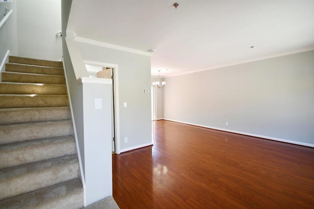 staircase with a notable chandelier, wood-type flooring, and ornamental molding