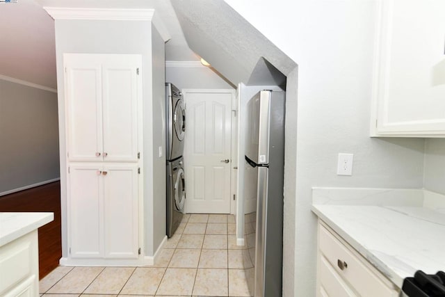 washroom featuring stacked washer / drying machine, light tile patterned floors, and crown molding