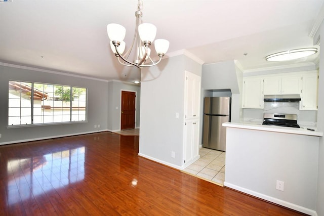 kitchen with white cabinetry, an inviting chandelier, light hardwood / wood-style flooring, crown molding, and appliances with stainless steel finishes