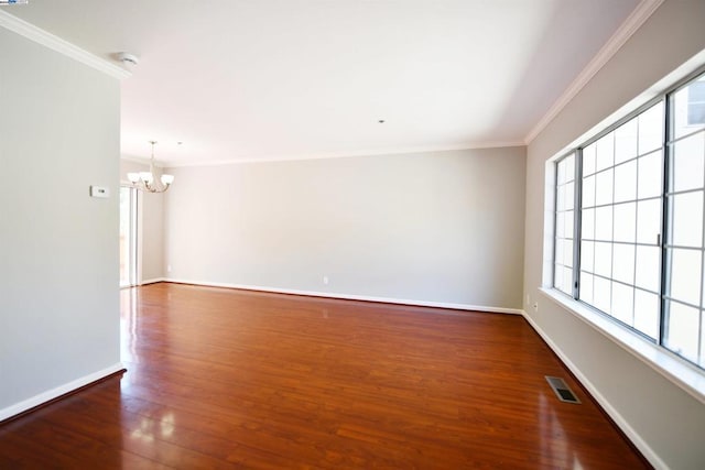 spare room featuring dark hardwood / wood-style flooring, ornamental molding, and a chandelier