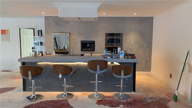 kitchen with stainless steel double oven, a kitchen bar, and ornamental molding