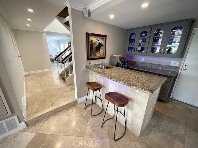 bar featuring stone counters, sink, and crown molding