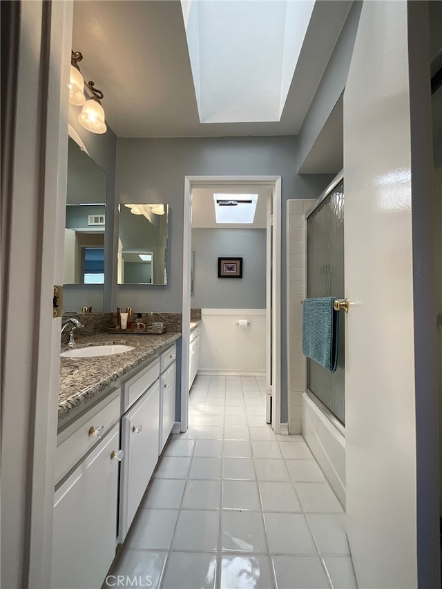 bathroom featuring combined bath / shower with glass door, a skylight, tile patterned floors, and vanity