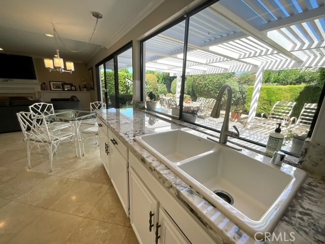 kitchen with hanging light fixtures, sink, light tile patterned floors, and white cabinets