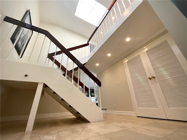 staircase with a towering ceiling and ornamental molding