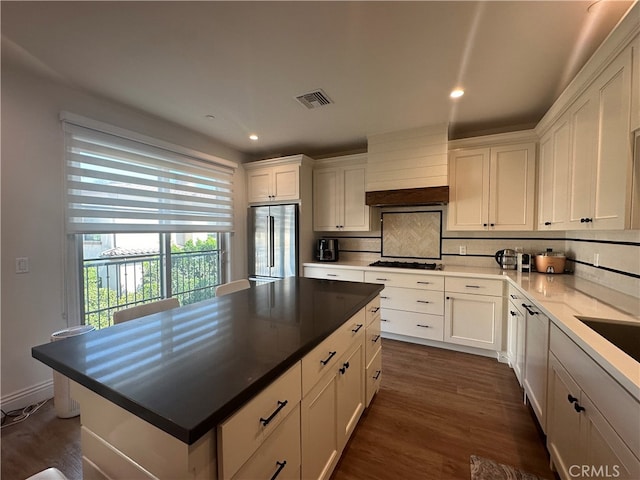 kitchen featuring stainless steel fridge, backsplash, dark hardwood / wood-style floors, a center island, and white cabinetry