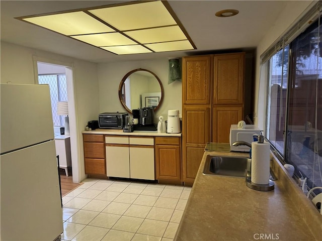 kitchen featuring light tile patterned floors, white fridge, plenty of natural light, and sink