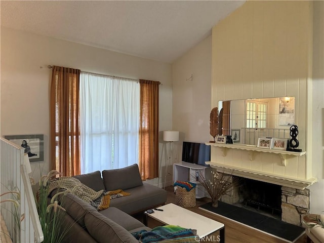 living room featuring hardwood / wood-style floors, a stone fireplace, and plenty of natural light