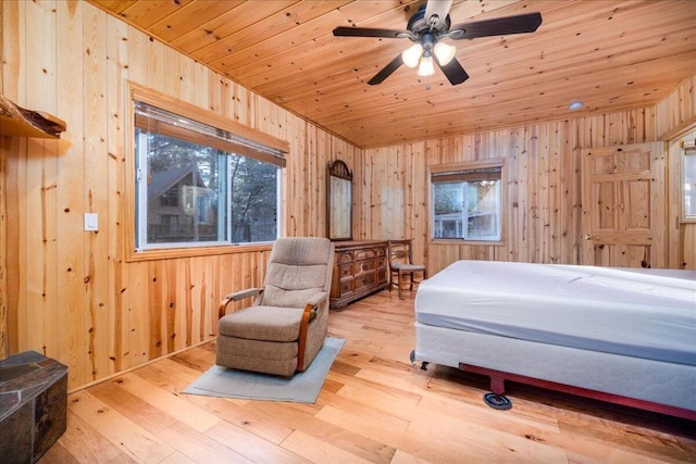 bedroom with ceiling fan, wood walls, wooden ceiling, and light wood-type flooring