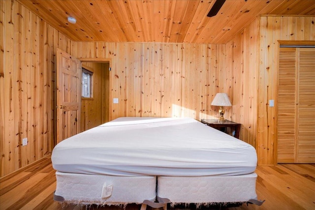 bedroom featuring wooden ceiling, ceiling fan, light hardwood / wood-style floors, and wood walls