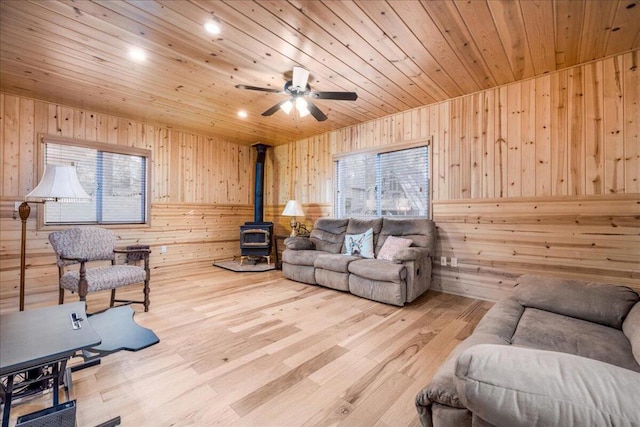 living room featuring a wood stove, wood walls, hardwood / wood-style floors, and a wealth of natural light