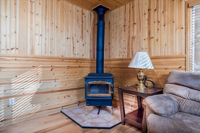 sitting room featuring a wood stove, wood walls, hardwood / wood-style flooring, and wooden ceiling