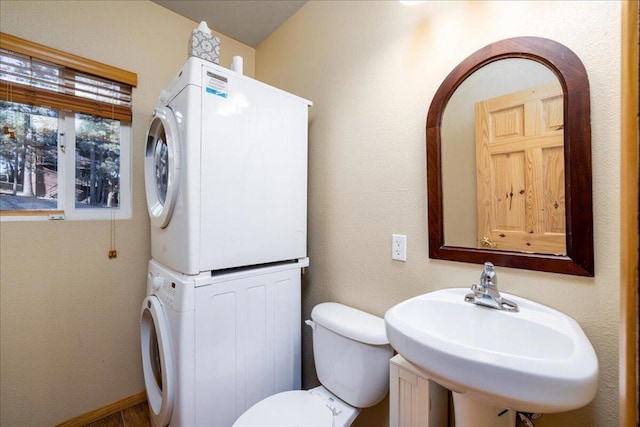 bathroom with stacked washing maching and dryer, sink, and toilet