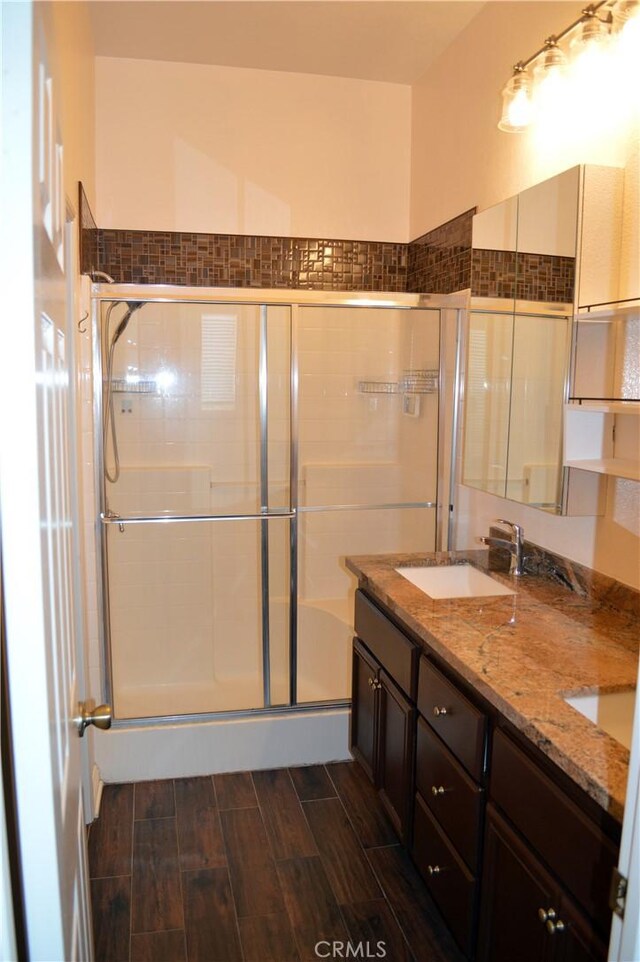 bathroom with a shower with door and vanity