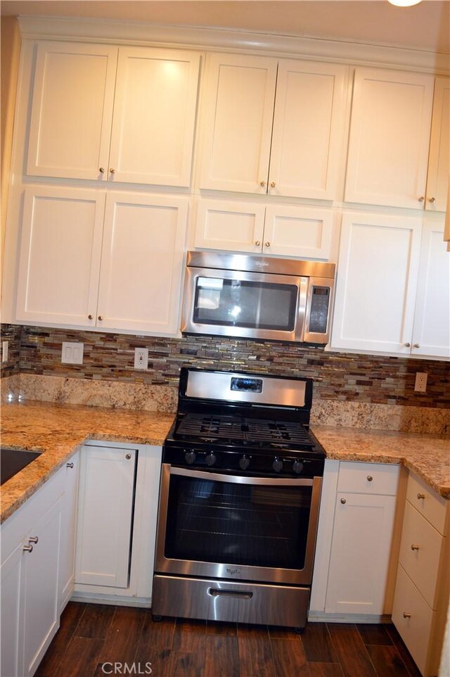 kitchen with light stone countertops, dark wood-type flooring, white cabinets, and stainless steel appliances