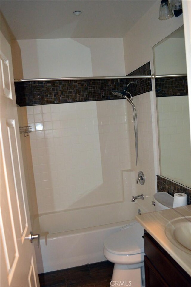 full bathroom with hardwood / wood-style floors, vanity, tiled shower / bath combo, and toilet