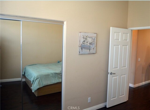 bedroom with dark hardwood / wood-style floors and a closet