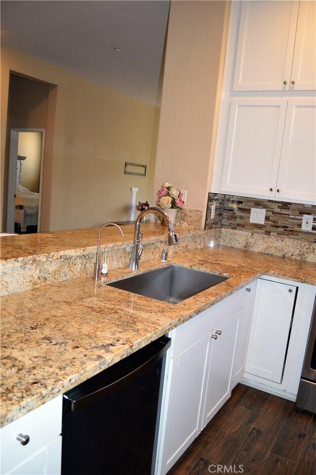 kitchen featuring sink, dark hardwood / wood-style floors, black dishwasher, light stone counters, and white cabinetry