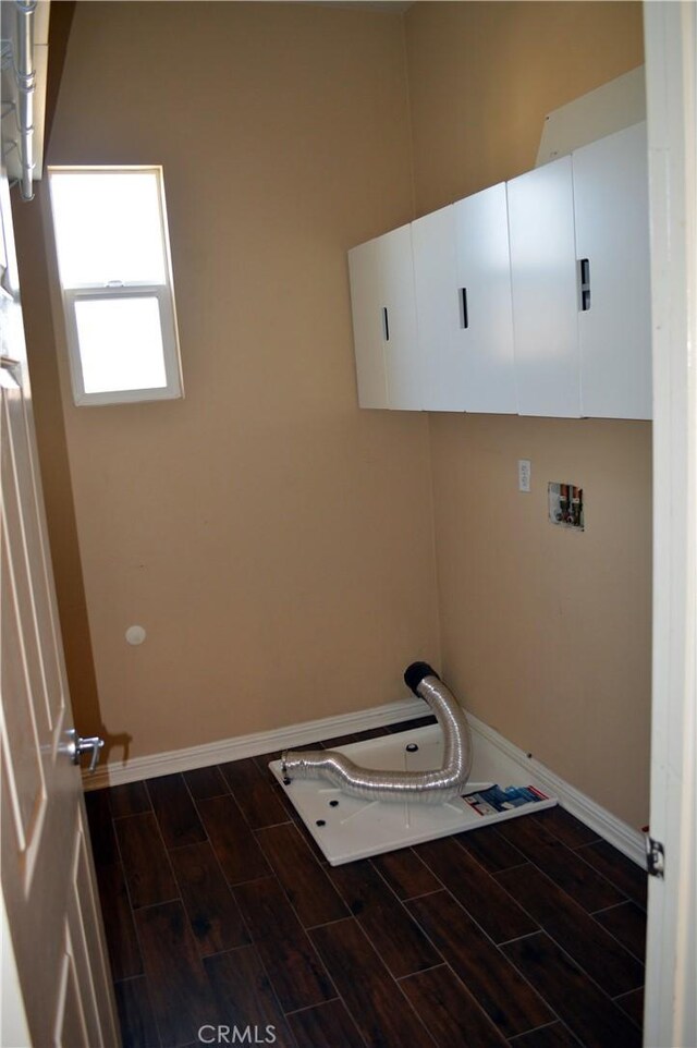 clothes washing area with dark wood-type flooring, cabinets, and washer hookup