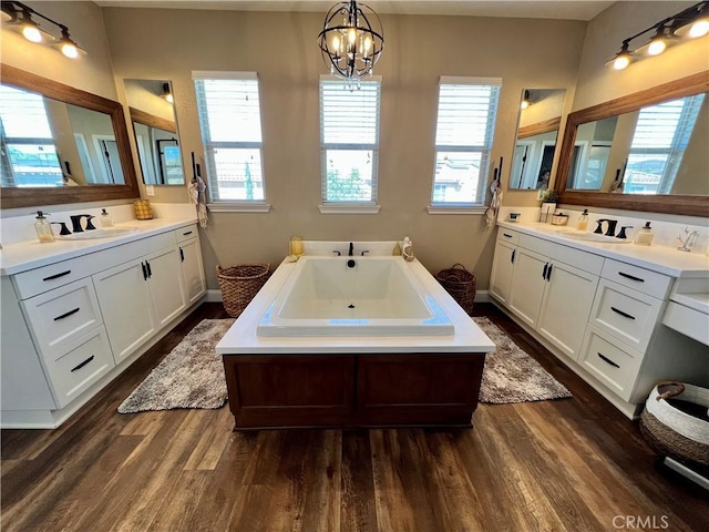 bathroom with hardwood / wood-style flooring, a tub to relax in, vanity, and a notable chandelier