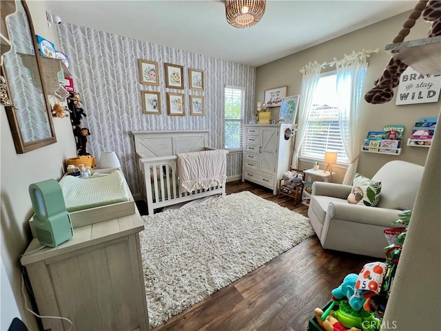 bedroom featuring a nursery area and dark hardwood / wood-style flooring