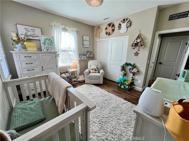 bedroom featuring dark wood-type flooring and a nursery area