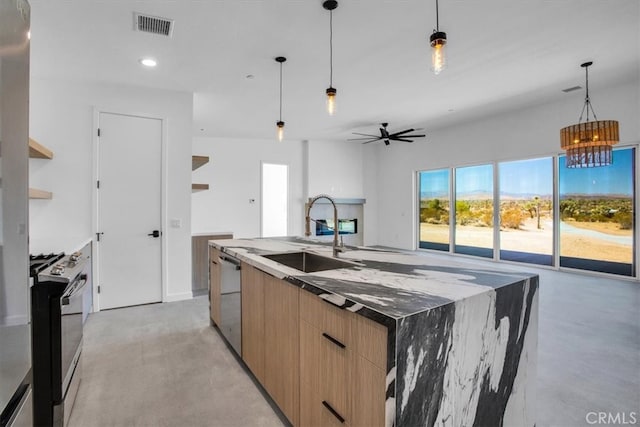 kitchen featuring sink, stainless steel appliances, decorative light fixtures, dark stone countertops, and a kitchen island with sink