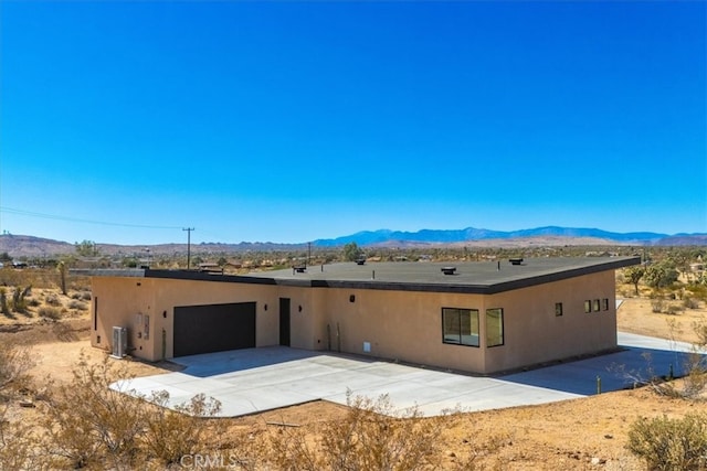 southwest-style home featuring a garage, a mountain view, and central AC unit