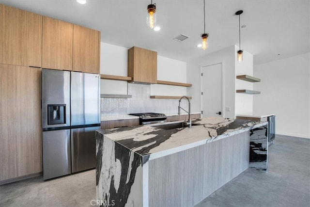 kitchen featuring hanging light fixtures, light stone counters, an island with sink, appliances with stainless steel finishes, and sink