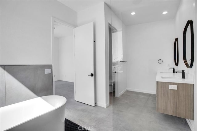 bathroom featuring concrete floors, vanity, and a bath