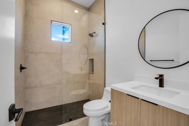 bathroom featuring vanity, toilet, and tiled shower