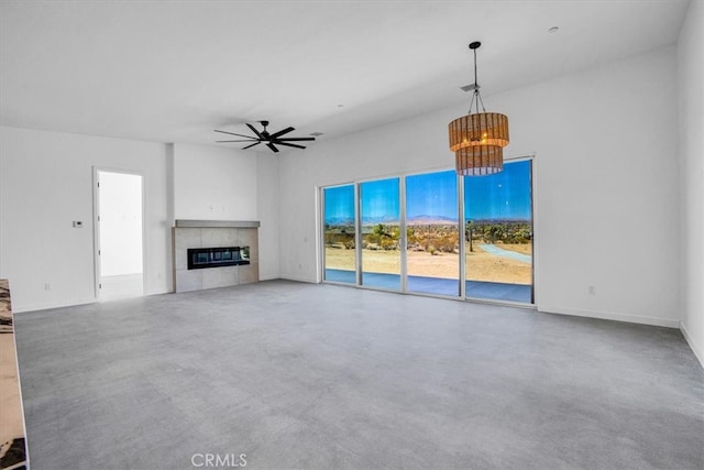 unfurnished living room with ceiling fan with notable chandelier and a fireplace