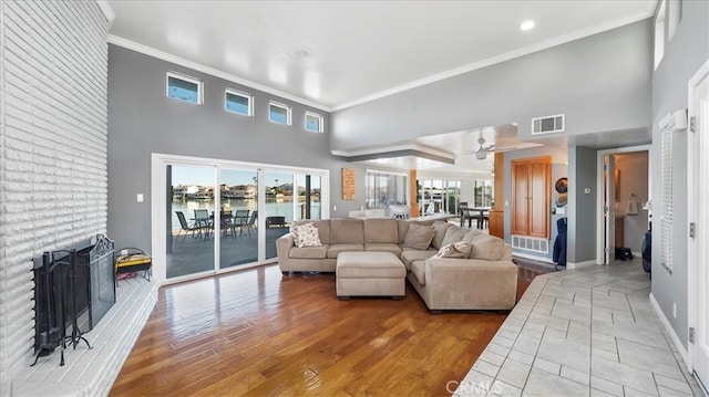 living room featuring ornamental molding, a fireplace, hardwood / wood-style floors, and a towering ceiling