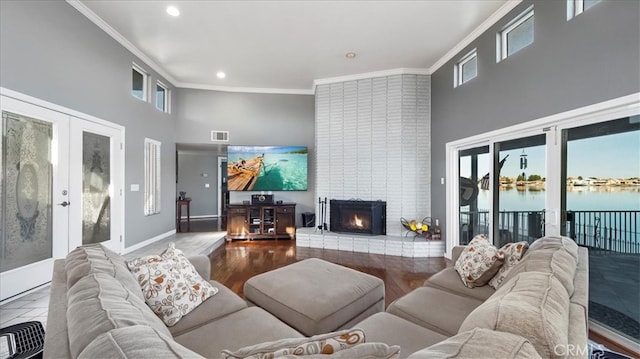 living room with a water view, a wealth of natural light, french doors, crown molding, and a towering ceiling