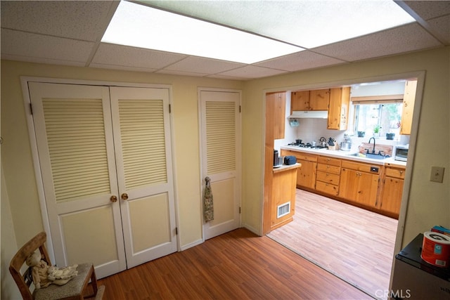 kitchen featuring light wood-type flooring, a paneled ceiling, sink, and white gas cooktop