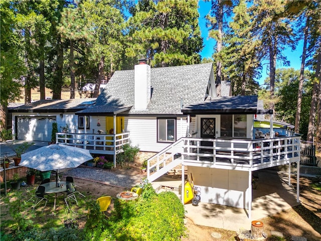 rear view of property with a garage and a wooden deck