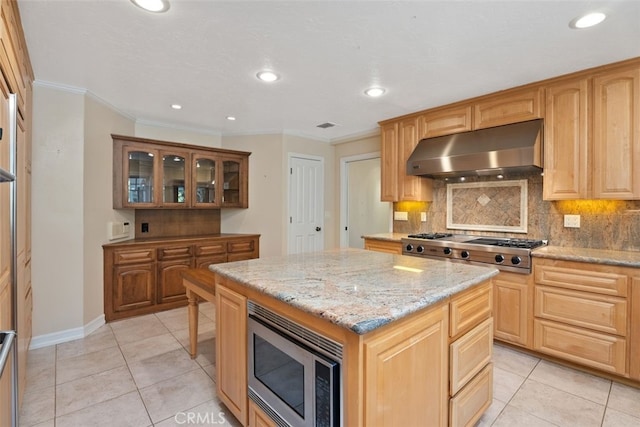 kitchen with appliances with stainless steel finishes, a center island, crown molding, and light tile patterned flooring