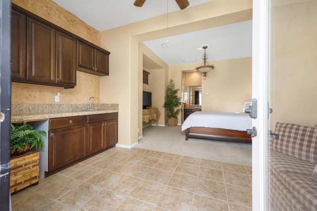 carpeted bedroom with ensuite bath, ceiling fan, and sink