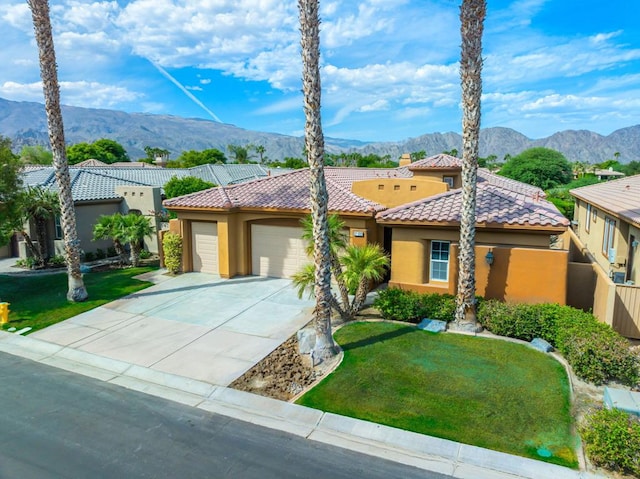 mediterranean / spanish house with a garage, a front yard, and a mountain view