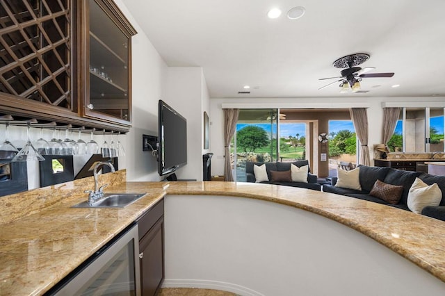 kitchen featuring dark brown cabinets, wine cooler, sink, and ceiling fan